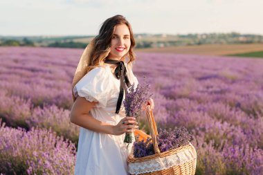 Lavanta tarlasında piknik sepeti olan güzel genç bir kadın.