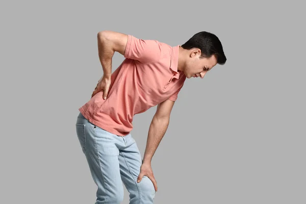 Young Man Suffering Back Pain Grey Background — Stock Photo, Image