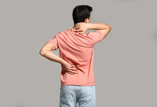 Young Man Suffering Back Pain Grey Background — Stock Photo, Image