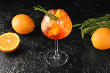 Lezzetli aperol spreyi kokteyli ve koyu arkaplanda taze portakallar.
