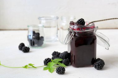 Bir kavanoz lezzetli böğürtlen reçeli ve hafif arkaplanda dut