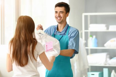 Modern kuru temizlemecide müşteriye kıyafet veren işçi