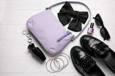 Moda çanta ve beyaz ahşap arka planda farklı aksesuarlar.