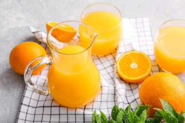 Hafif arka planda bir sürahi ve bir bardak lezzetli portakal suyu