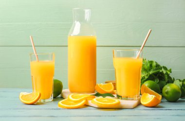 Sürahi ve portakal suyu renkli ahşap arka planda.