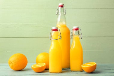 Renkli ahşap arka planda lezzetli portakal suyu şişeleri