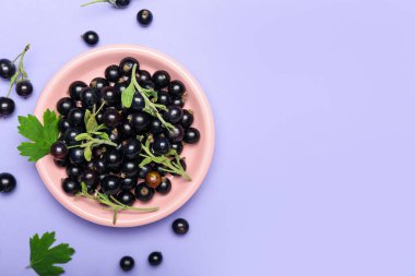 Renk arkaplanında olgun siyah frenk üzümü olan tabak