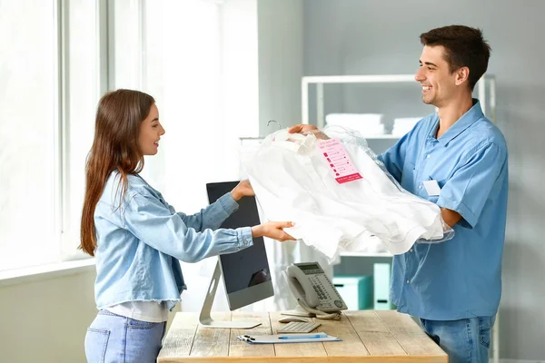 Modern kuru temizlemecide müşteriye kıyafet veren işçi