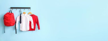 Modern okul üniforması ve sırt çantası renkli duvarda asılı.