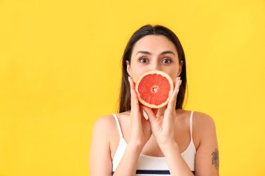 Arkaplanda greyfurt olan güzel bir genç kadın.