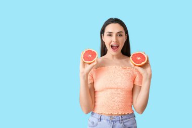 Arka planında greyfurt olan şaşırmış genç bir kadın.