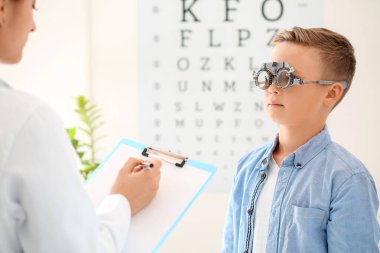 Küçük çocuk klinikte göz testi yaptırıyor.