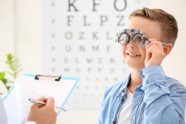 Küçük çocuk klinikte göz testi yaptırıyor.
