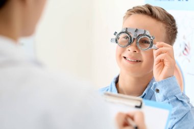 Küçük çocuk klinikte göz testi yaptırıyor.