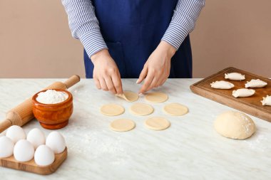 Mutfaktaki masada lezzetli börekler hazırlayan kadın, yakın plan.