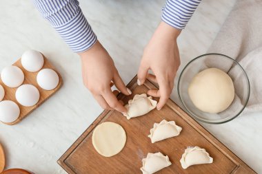 Kadın hafif arka planda lezzetli börekler hazırlıyor.