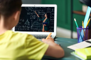 Küçük çocuk evde online matematik okuyor.