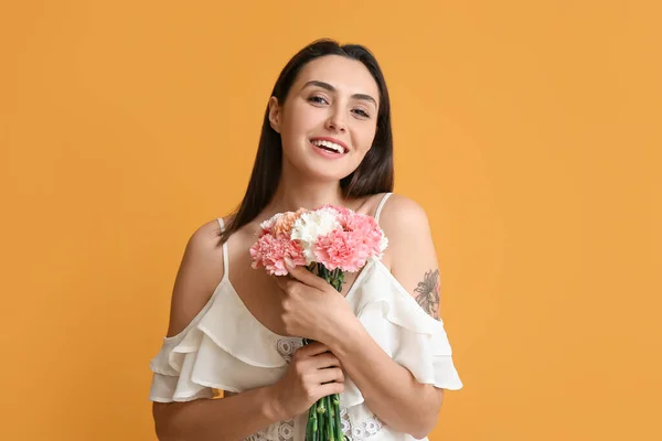 色の背景に美しいカーネーションの花を持つ若い女性 — ストック写真