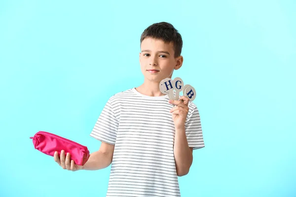 鉛筆ケースと色の背景に文字のセットを持つ小さな男の子 — ストック写真