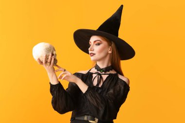 Young witch with skull on color background clipart