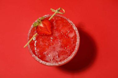 Renkli arkaplanda bir bardak lezzetli çilekli margarita.