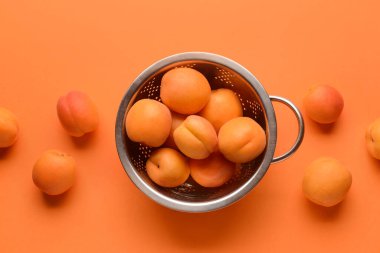 Renk arkaplanında lezzetli olgun kayısılara sahip Colander