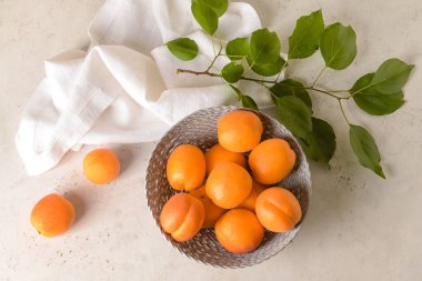 Hafif arka planda lezzetli olgun kayısılarla dolu bir kase.