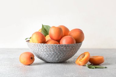 Hafif arka planda lezzetli olgun kayısılarla dolu bir kase.