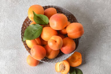 Gri arka planda lezzetli olgun kayısılarla dolu bir kase.