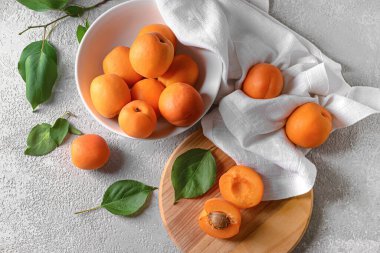 Gri arka planda lezzetli olgun kayısılarla dolu bir kase.