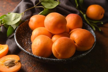 Arkaplanda lezzetli olgun kayısılarla dolu bir kase.