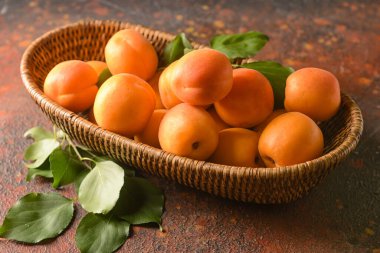 Arkaplanda lezzetli olgun kayısılar olan sepet.