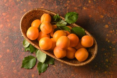 Arkaplanda lezzetli olgun kayısılar olan sepet.