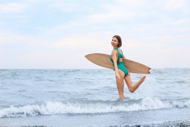 Plajda sörf tahtası olan güzel bir genç kadın.