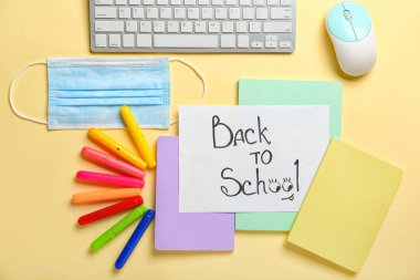 Renk arkaplan üzerinde metin ile okula dönüş, kırtasiye seti ve tıbbi maske