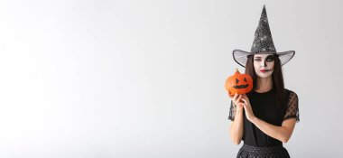 Cadılar Bayramı için cadı gibi giyinmiş güzel bir kadın. Arka planda ışık ve metin için yer var.