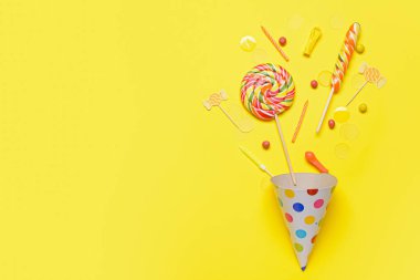 Parti şapkası, mumlar ve renkli arkaplanda şekerler