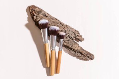 Beyaz arkaplanda ağaç kabuğu olan makyaj fırçaları