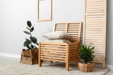 Yastıklı çekmeceler ve ışık duvarının yanında bitkiler.