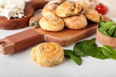 Beyaz ahşap arka planda ıspanak ve peynir ile doldurulmuş puf böreği.