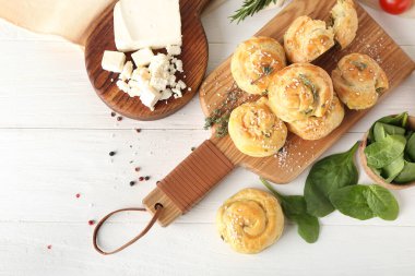 Beyaz ahşap arka planda ıspanak ve peynir ile doldurulmuş puf böreği.