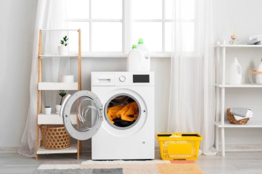 Çamaşırları banyonun içinde olan modern çamaşır makinesi.