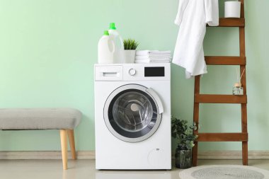 Çamaşırları banyonun içinde olan modern çamaşır makinesi.