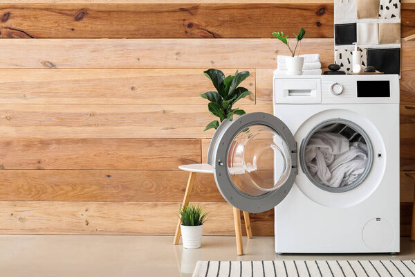 Modern washing machine with laundry in interior of bathroom