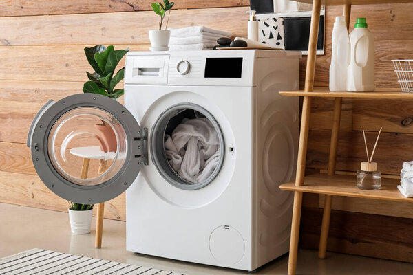 Modern washing machine with laundry in interior of bathroom