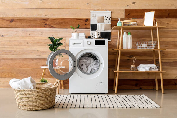 Modern washing machine with laundry in interior of bathroom