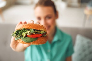 Evde lezzetli vejetaryen burgeri olan genç bir kadın.