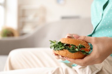 Evde lezzetli vejetaryen burgeri olan genç bir kadın, yakın plan.