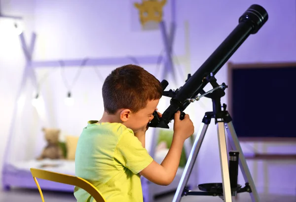 Little boy with telescope looking at stars in evening