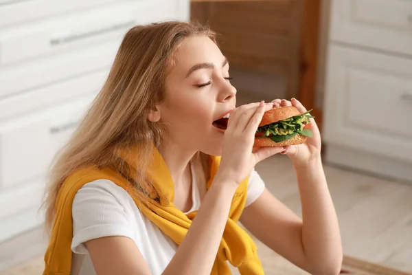 Jovem Mulher Comendo Saboroso Hambúrguer Vegan Cozinha — Fotografia de Stock